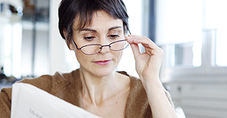 woman moving glasses down to read a book