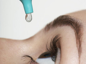 a person putting an eye drop into eye before cataract surgery
