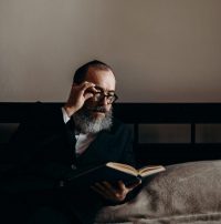 man wearing reading glasses to see a book