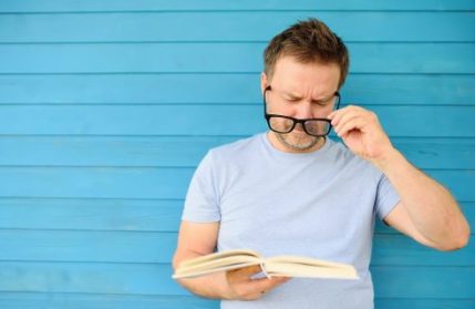 Man reading book putting glasses on. Reading glasses + RLE