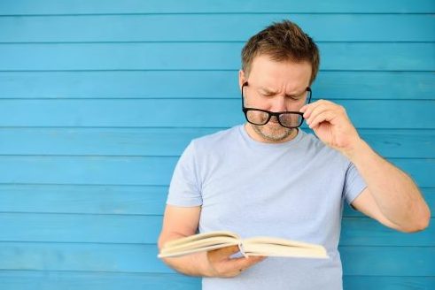 Man reading book putting glasses on. Reading glasses + RLE