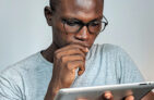 Man wearing glasses reading a tablet